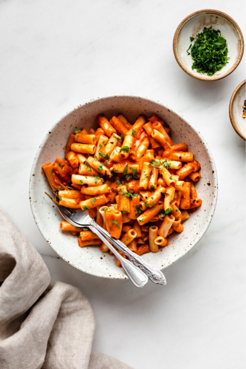 red pepper ziti pasta with green parsley in a white bowl