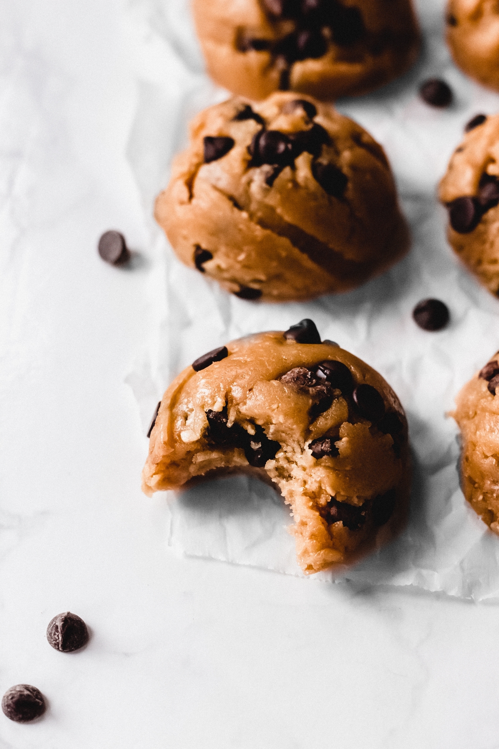 a close up of a chocolate chip cookie dough ball with a bite missing