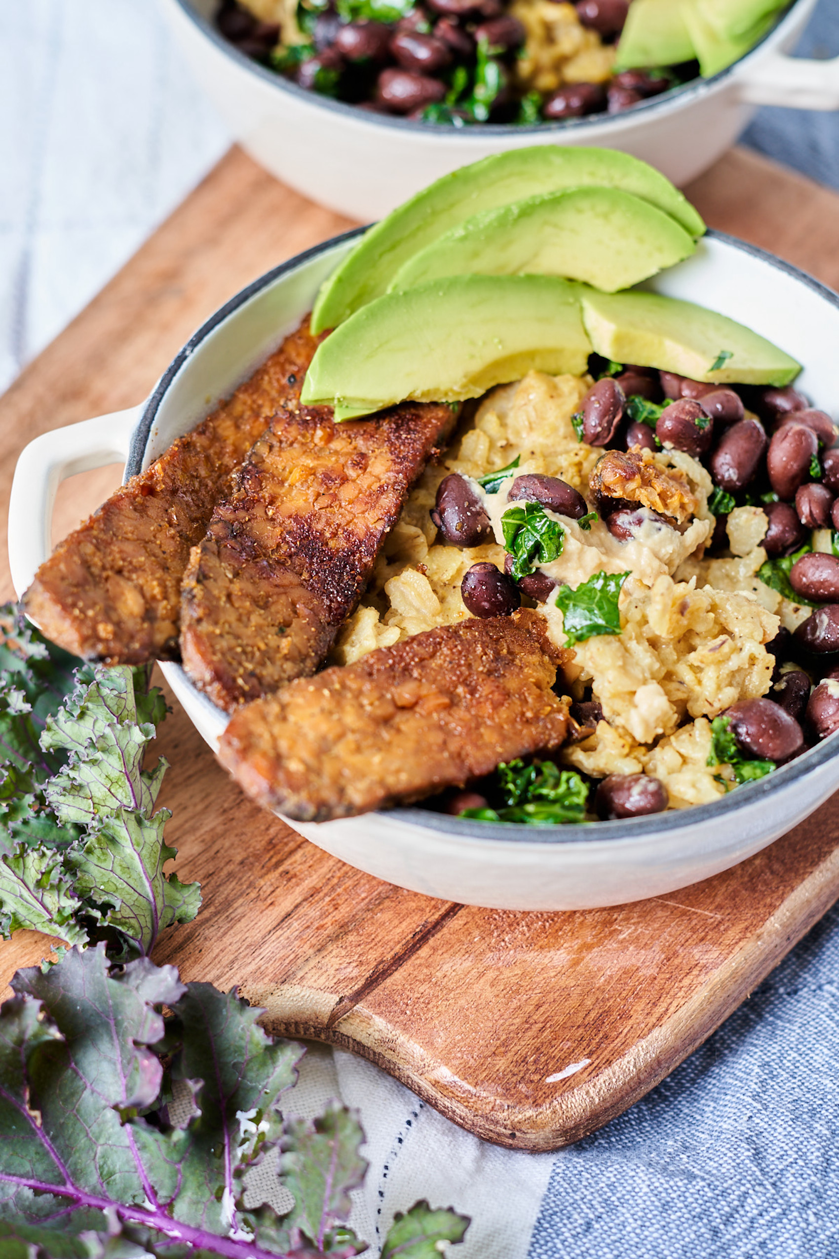 a bowl of oats topped with tempeh bacon, beans and avocado