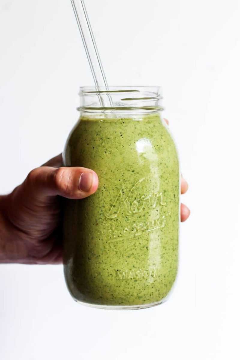 hand holding mason jar of green banana matcha smoothie with straw