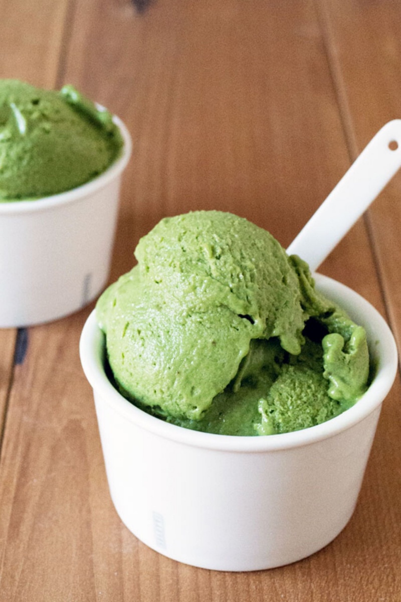white cup with two scoops of bright green ice cream with a white spoon