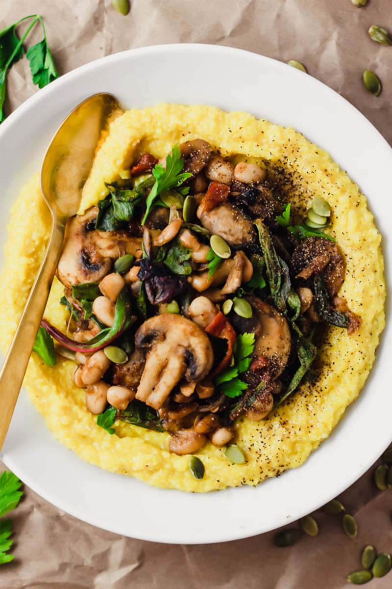 brown paper bag background with white bowl of yelllow polenta and mushrooms on top