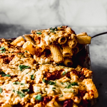 a scoop of baked ziti being lifted out of a casserole dish