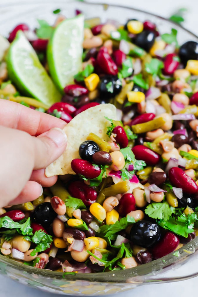 hand holding chip dipping into bean salad