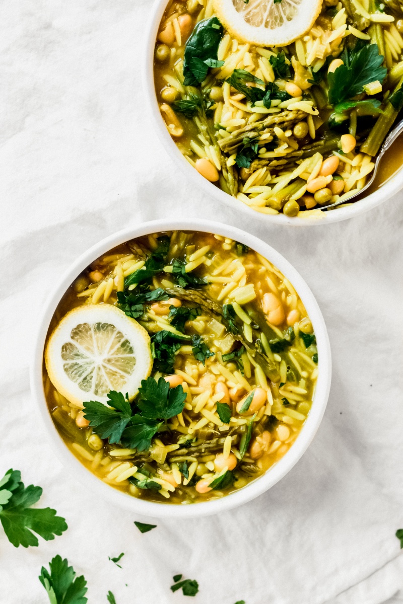 two bowls of vegan white bean soup with lemon wedges