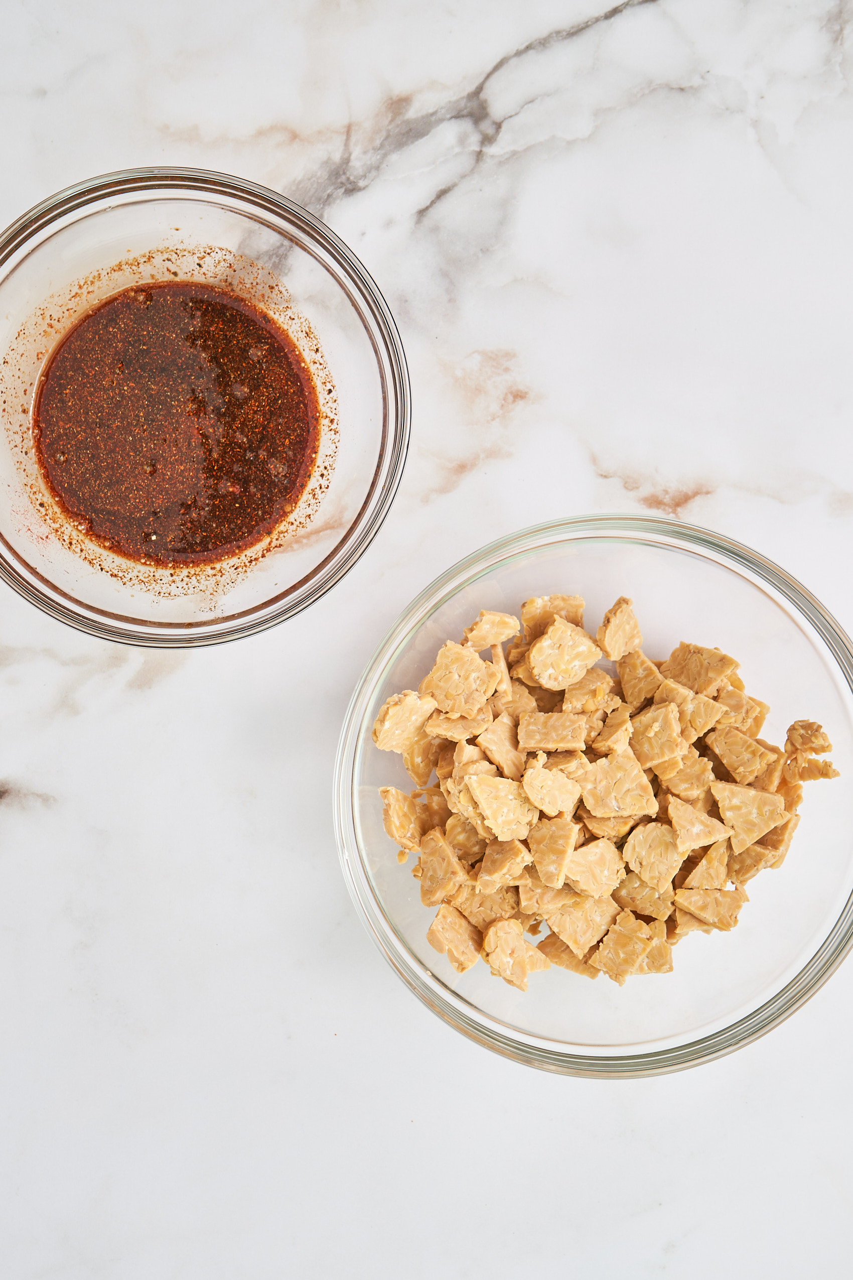 a bowl of cubed tempeh and a separate bowl of marinade