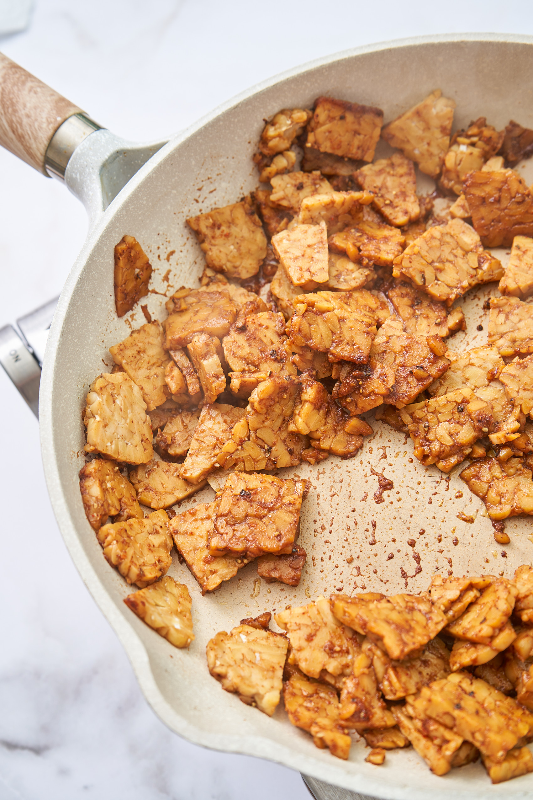 a pan with diced tempeh being fried on the stove