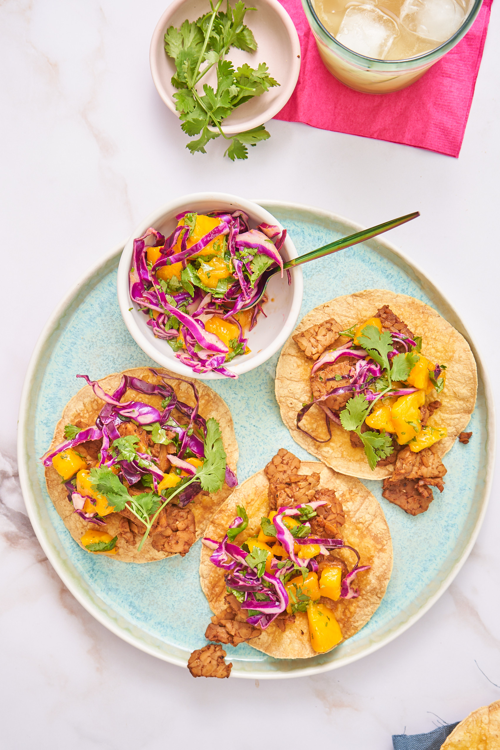 an overhead shot of three tostadas each topped with smoky tempeh and a mango slaw