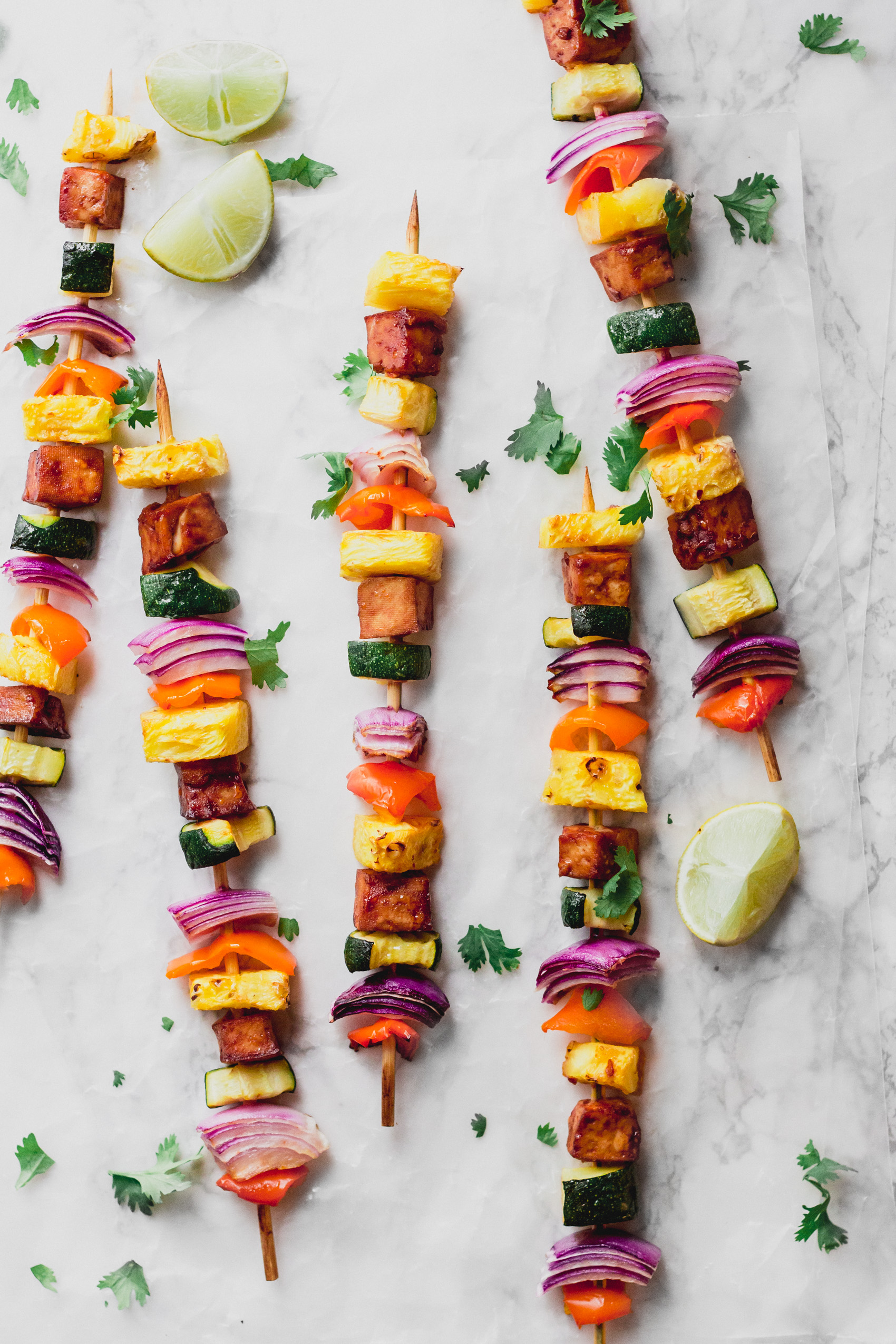 a collection of five skewers each with vegetables, pineapple and bbq tofu