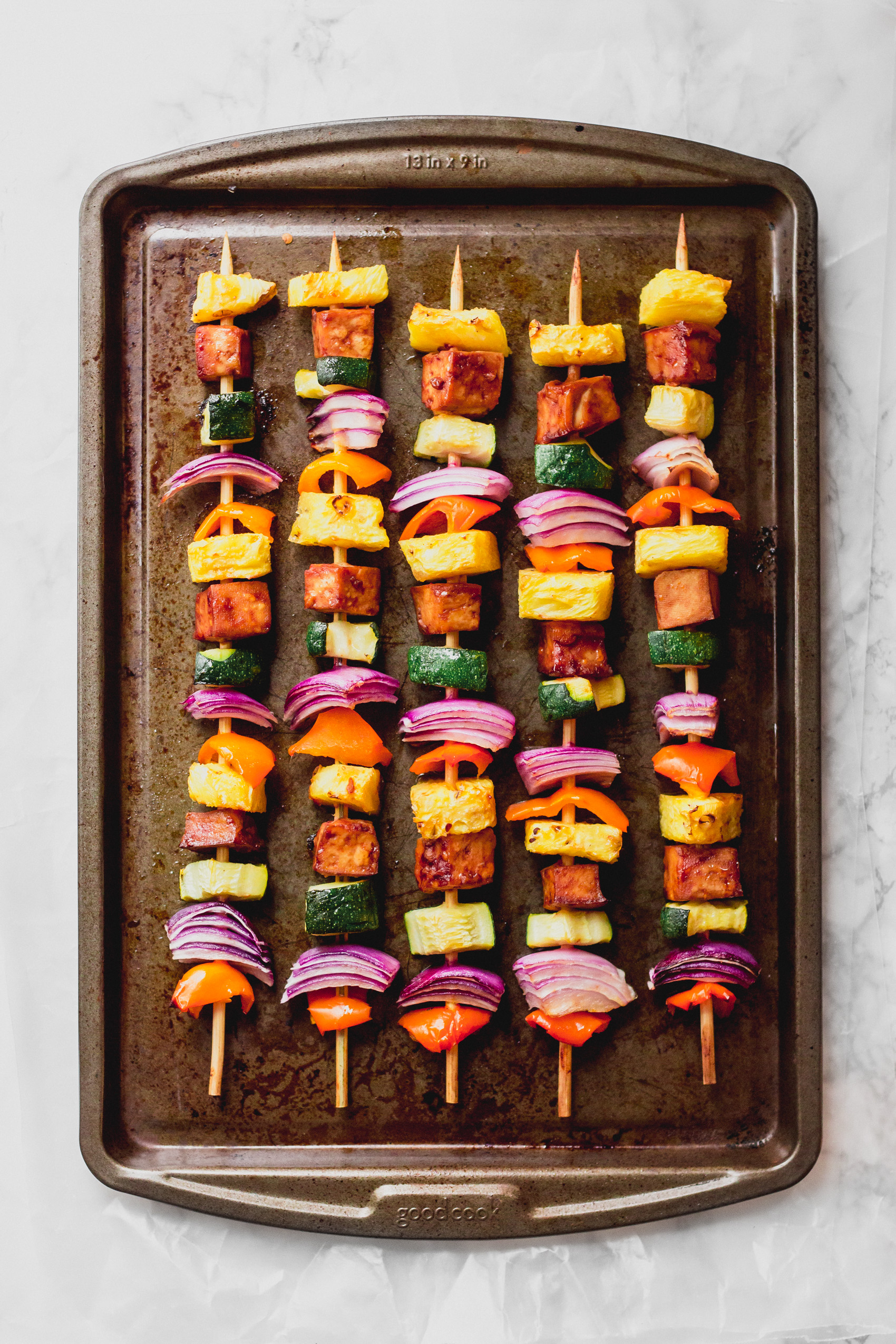 a sheet tray holding five vegetable skewers