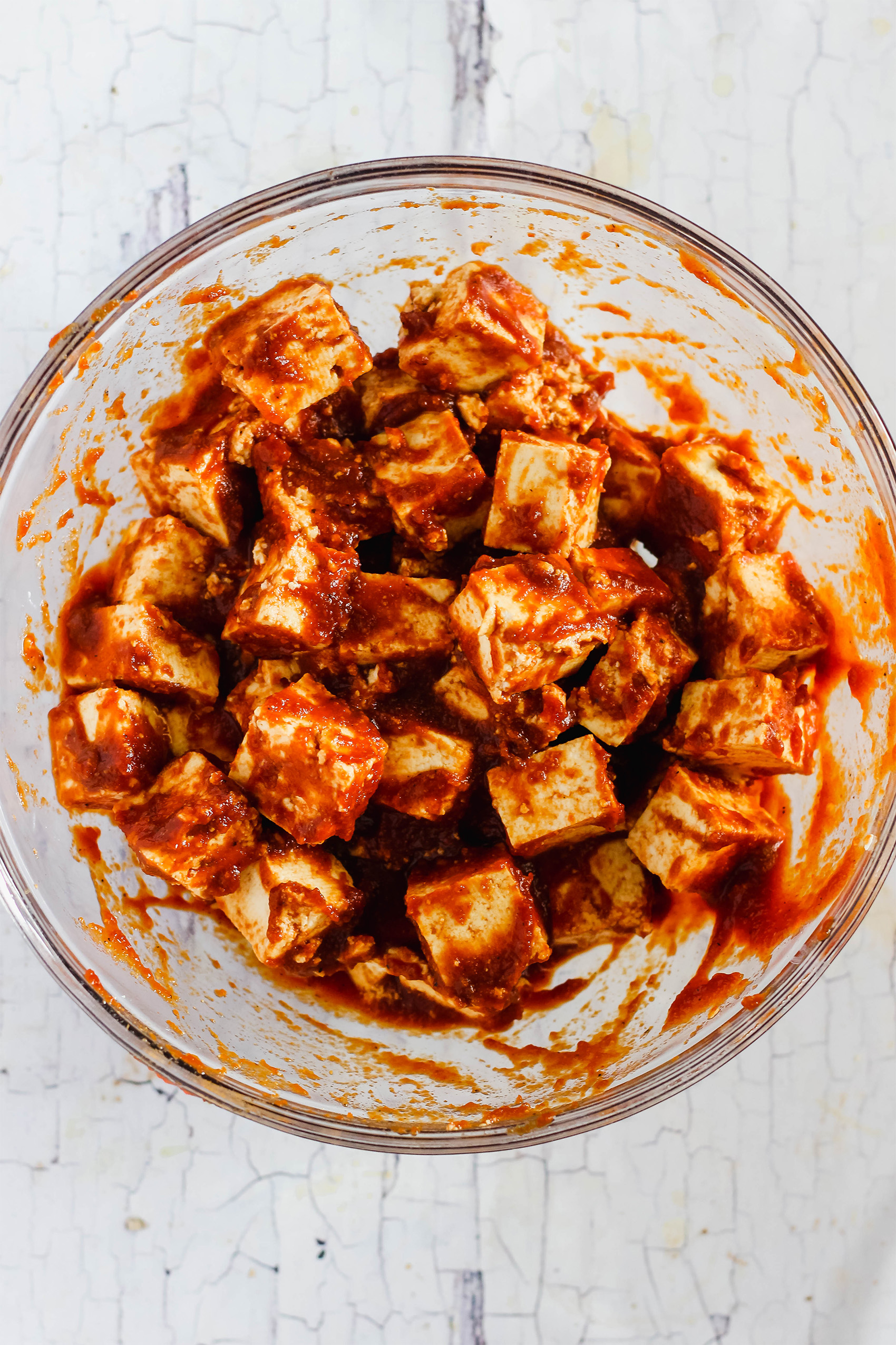 a bowl of tofu cubes being marinated in bbq sauce