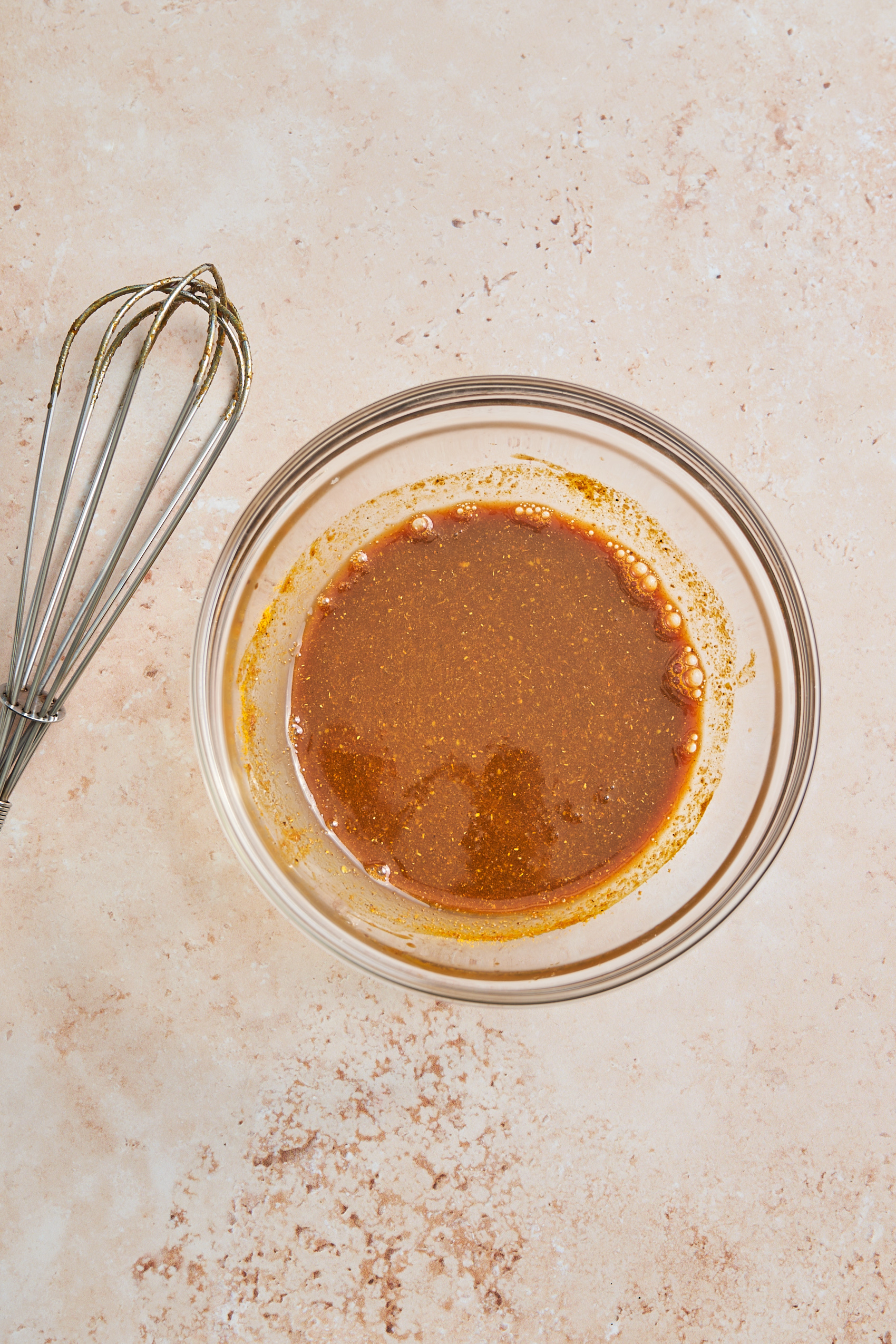 a bowl of curried vinaigrette next to a whisk