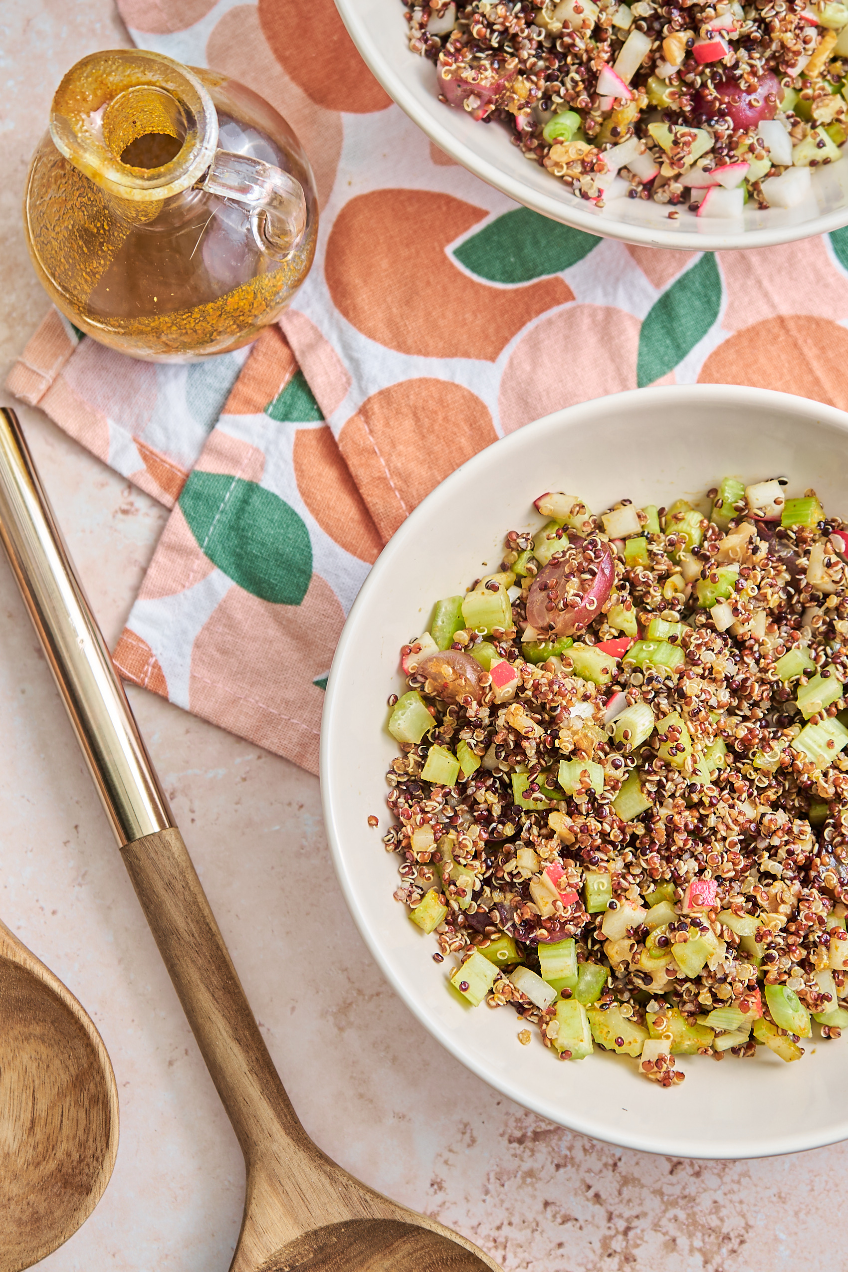 a bowl of curry quinoa salad next to salad tossing utensils