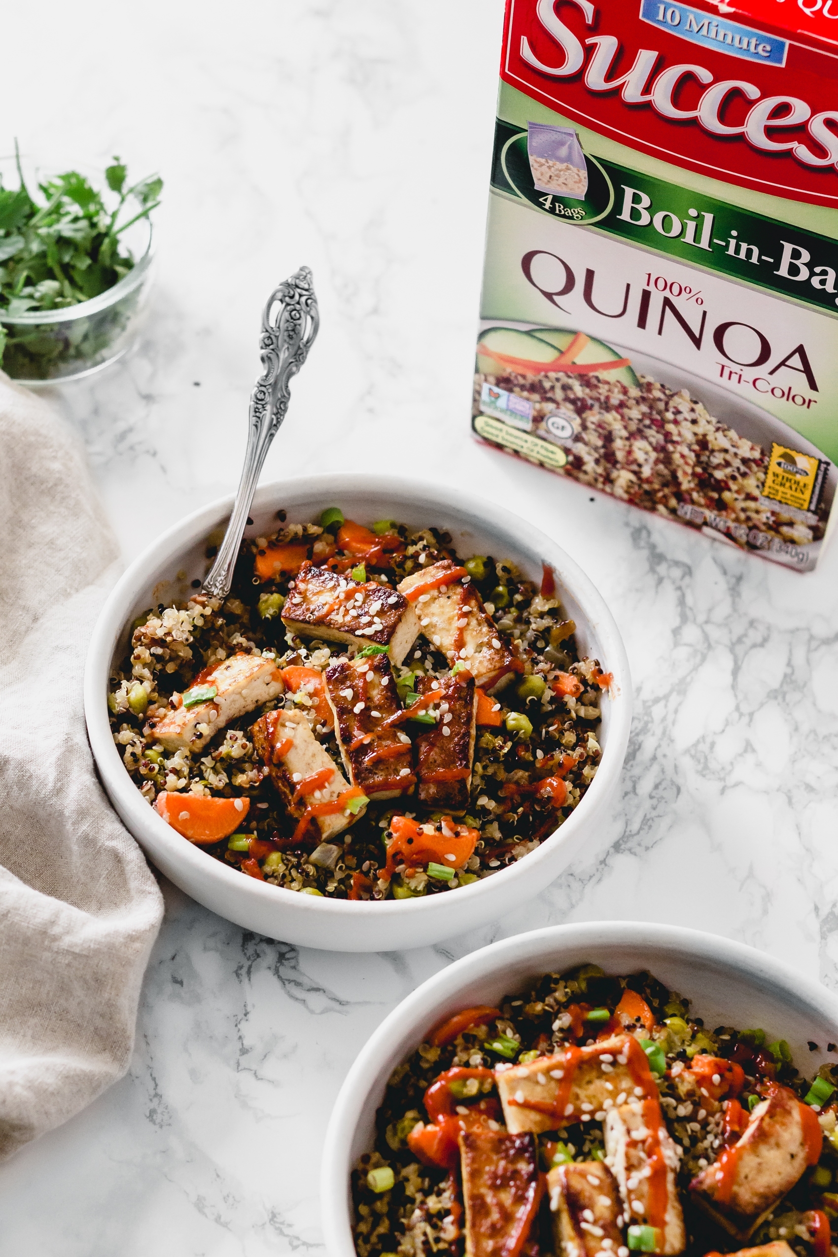 a box of tricolor quinoa next to a bowl of stir fried tofu and quinoa