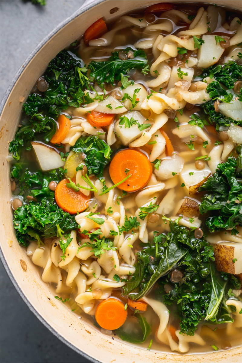 vegan soup in a pot with noodles and kale shot from overhead