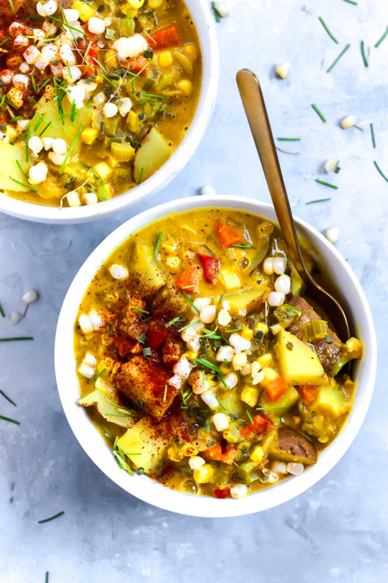 vegan soup with corn and potatoes with a gold spoon