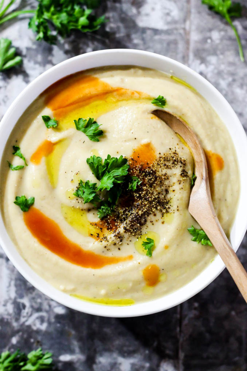 vegan soup with pepper on top and a wooden spoon 