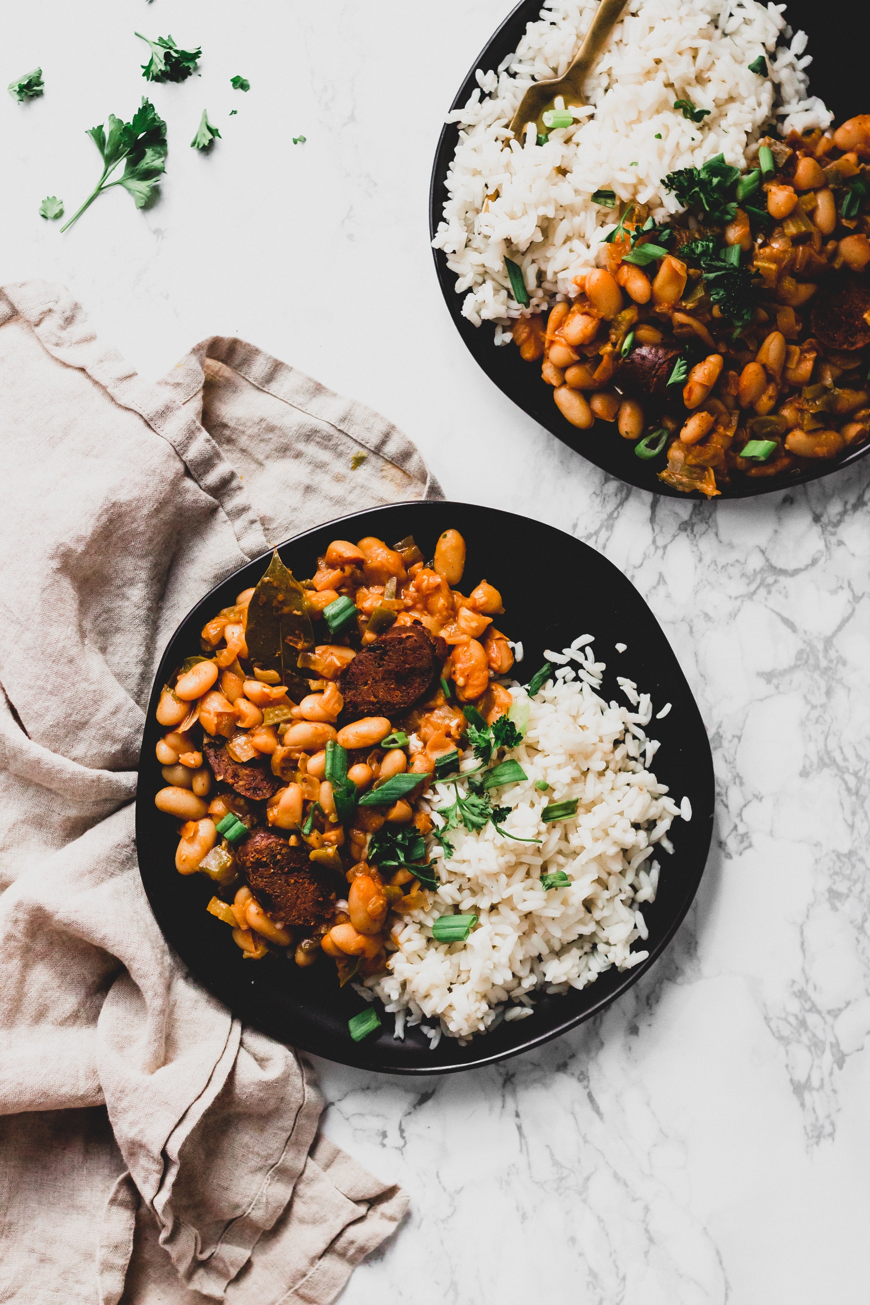 two plates of vegan white beans and rice topped with parsley