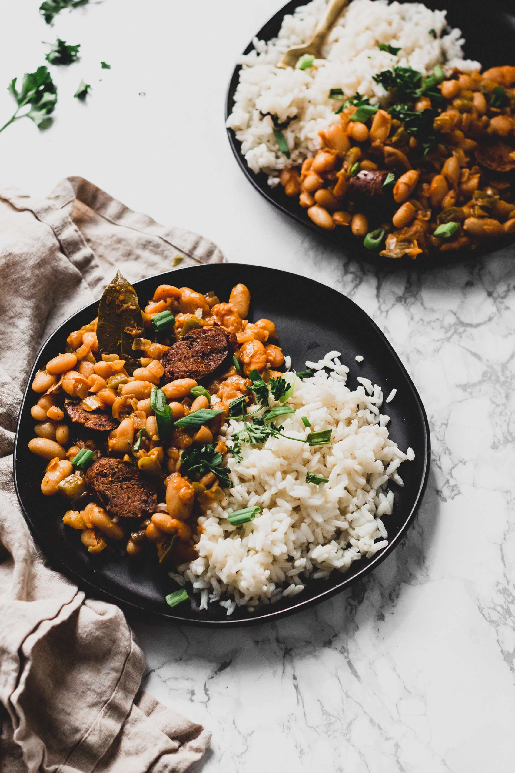 a closeup of two plates of vegan white beans and rice topped with fresh parsley