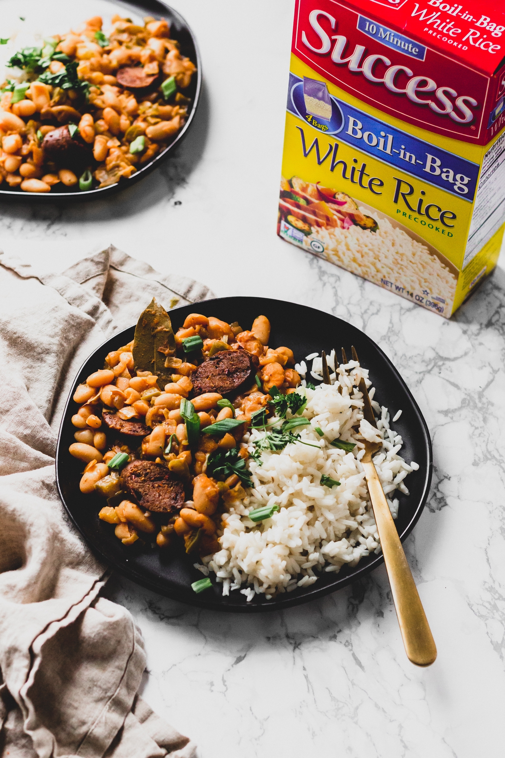 two plates of cajun white beans and rice served next to a box of Success instant rice