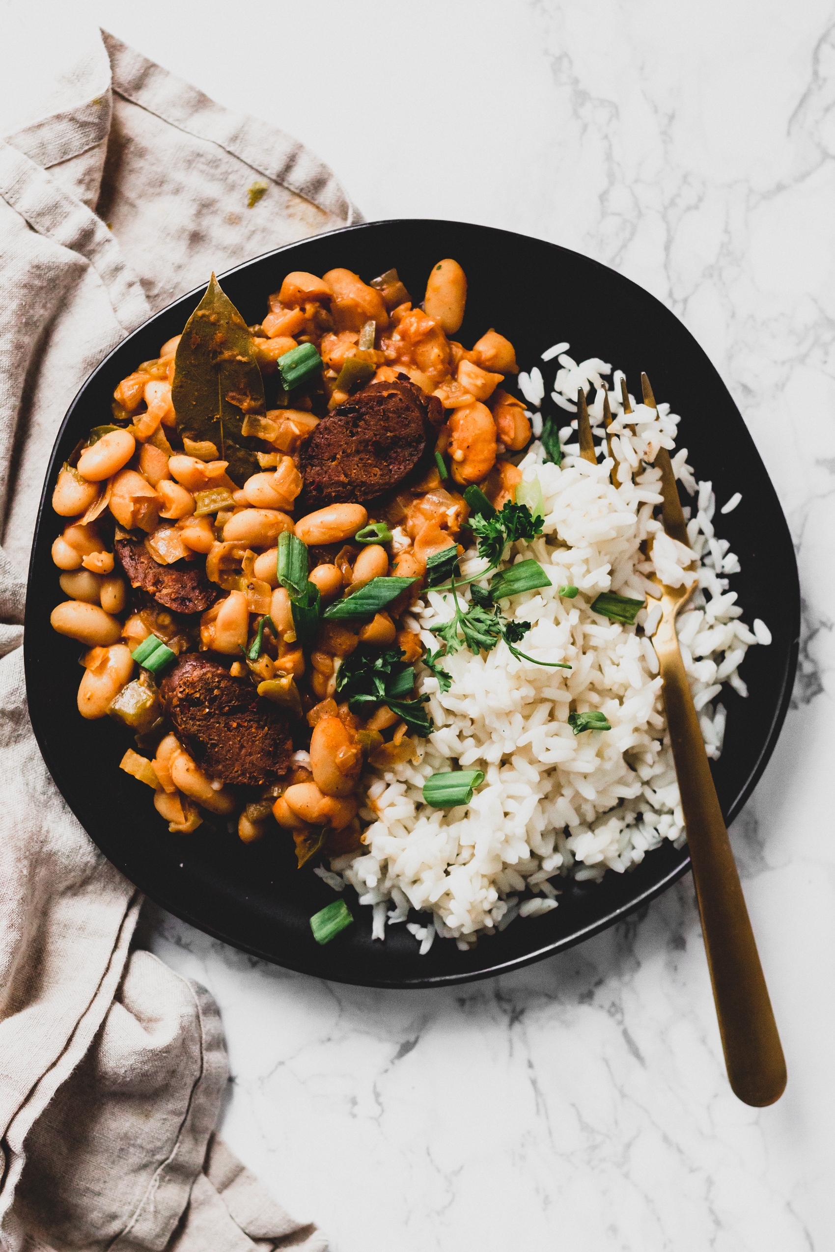 a plate of white rice served with cajun white beans topped with fresh parsley