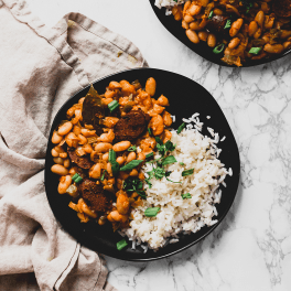 a plate of white beans and white rice topped with chopped parsley