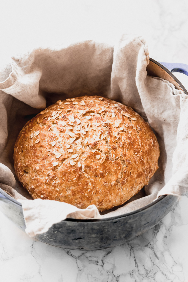 side view of a round loaf of bread on top of a napkin in a Dutch oven