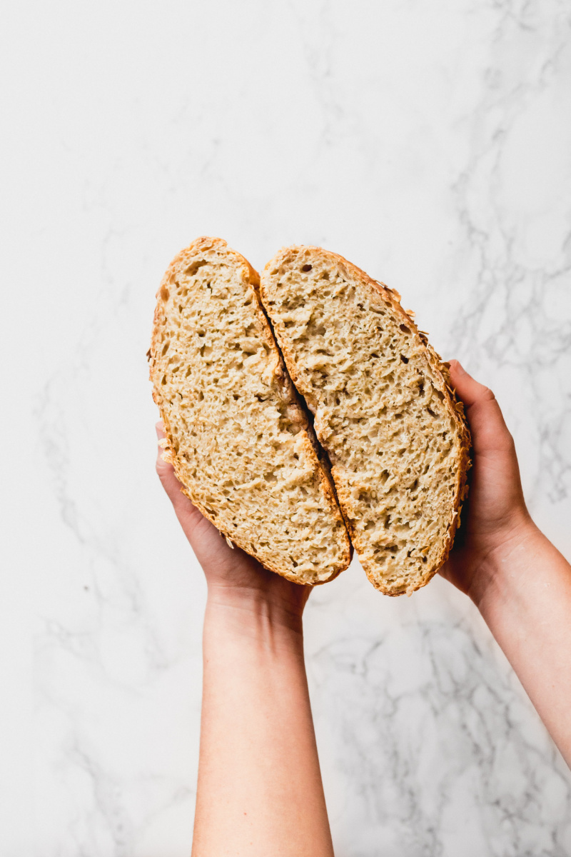 two hands holding a loaf cut in half