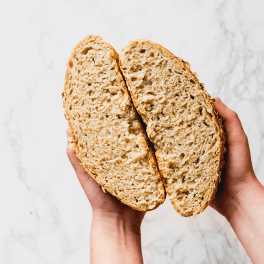 two hands holding two halves of a loaf of bread