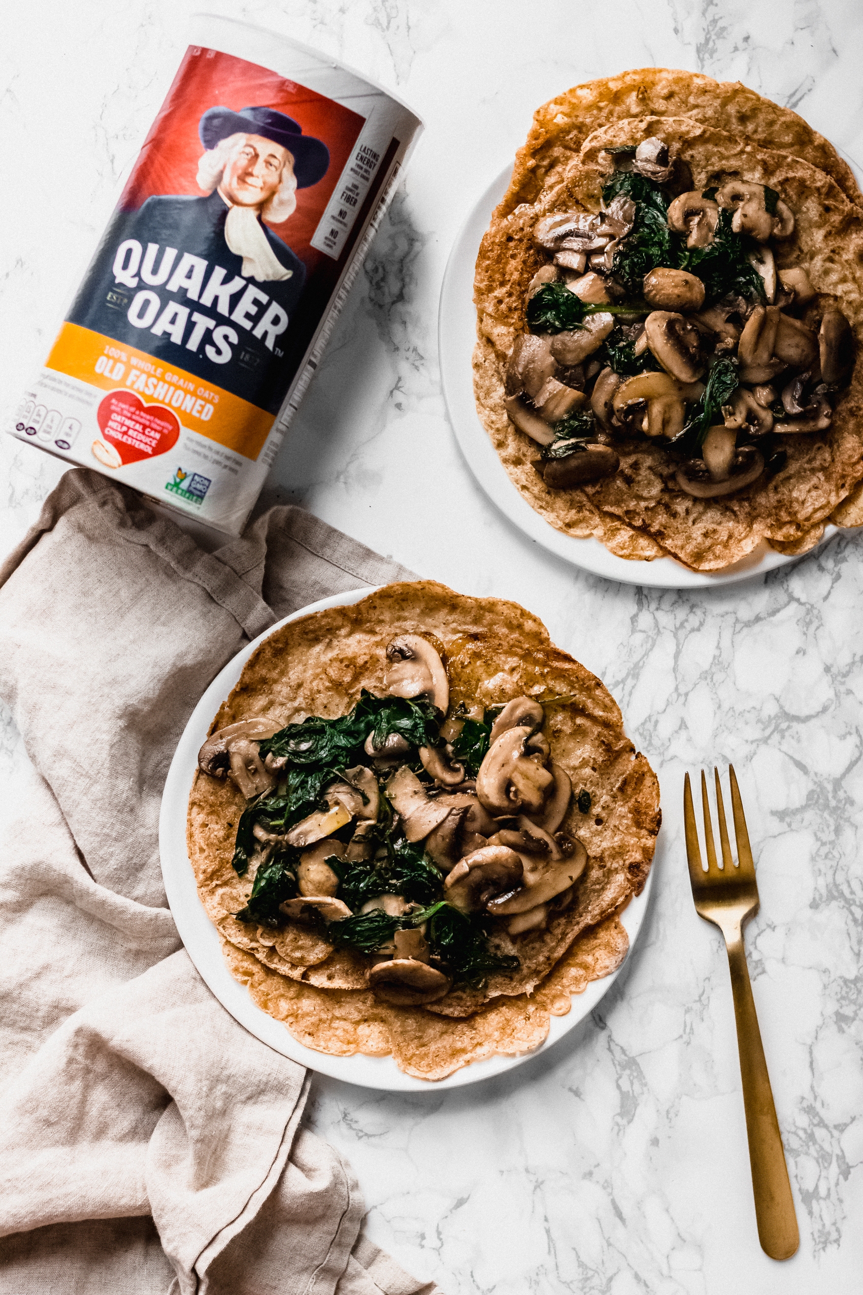 two crepes topped with mushrooms and spinach next to a container of oats