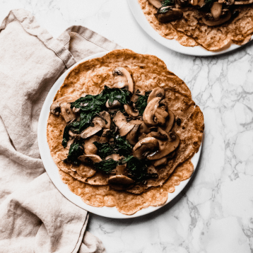 square image of oat crepes with sautéed mushrooms and spinach on top