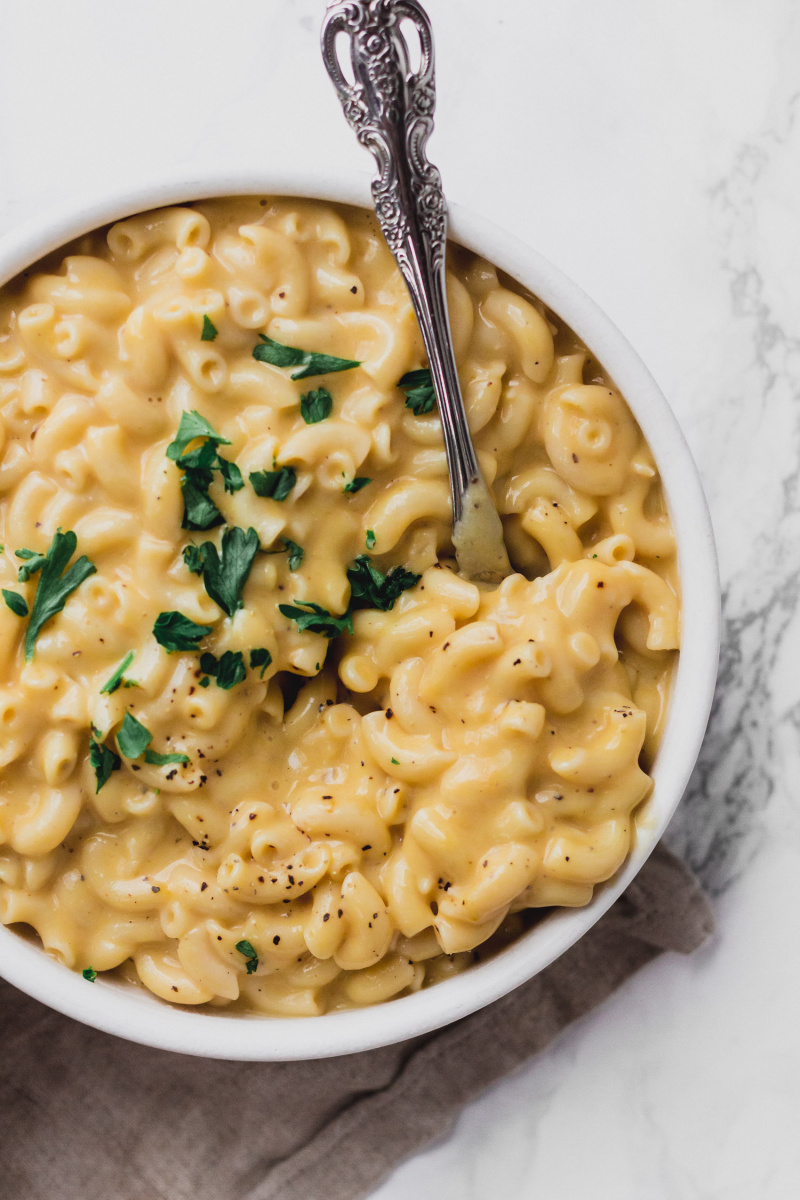 close-up of spoon in a bowl of vegan macaroni and cheese with chopped parsley on top