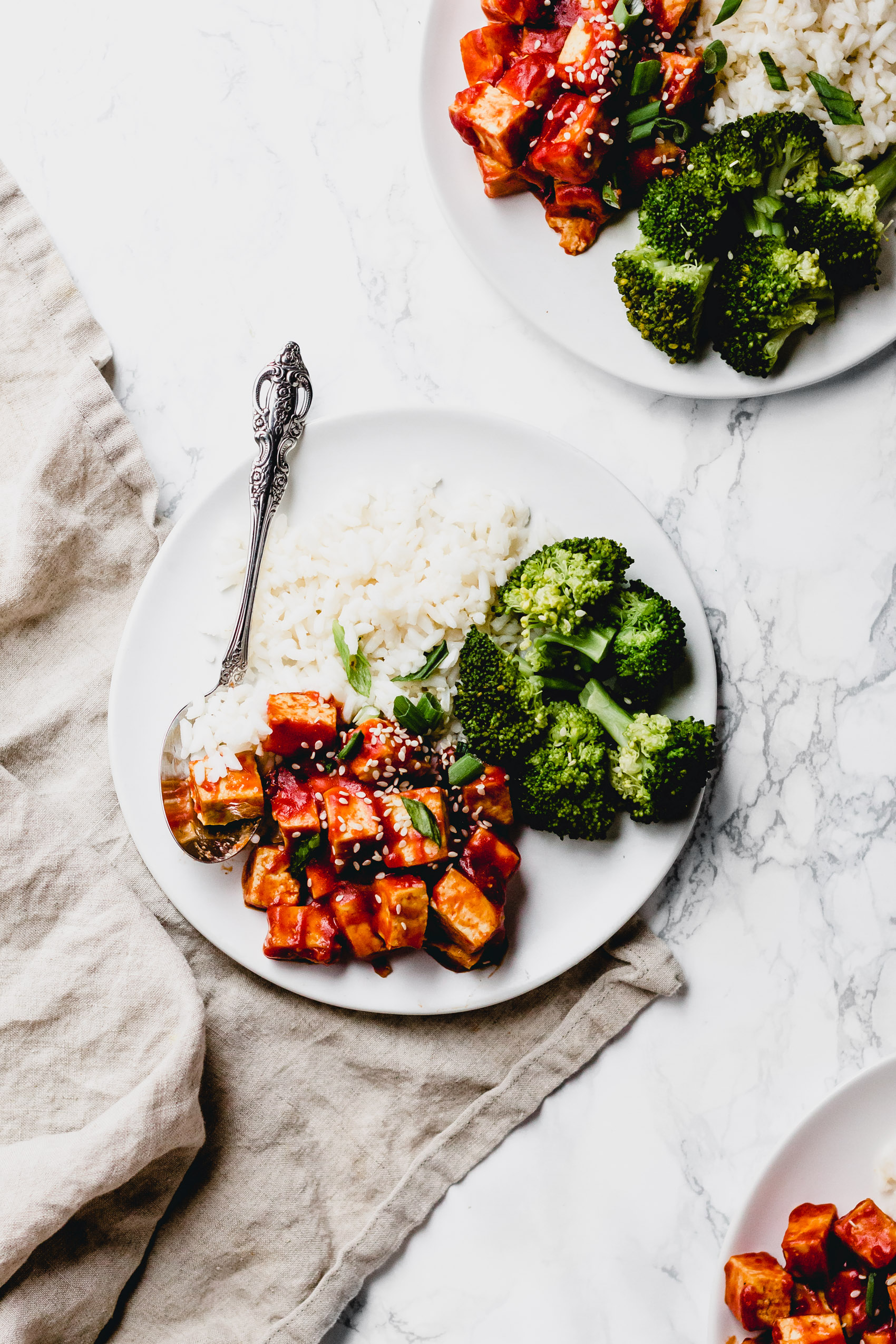 three plates of tofu in red sauce with broccoli and white rice