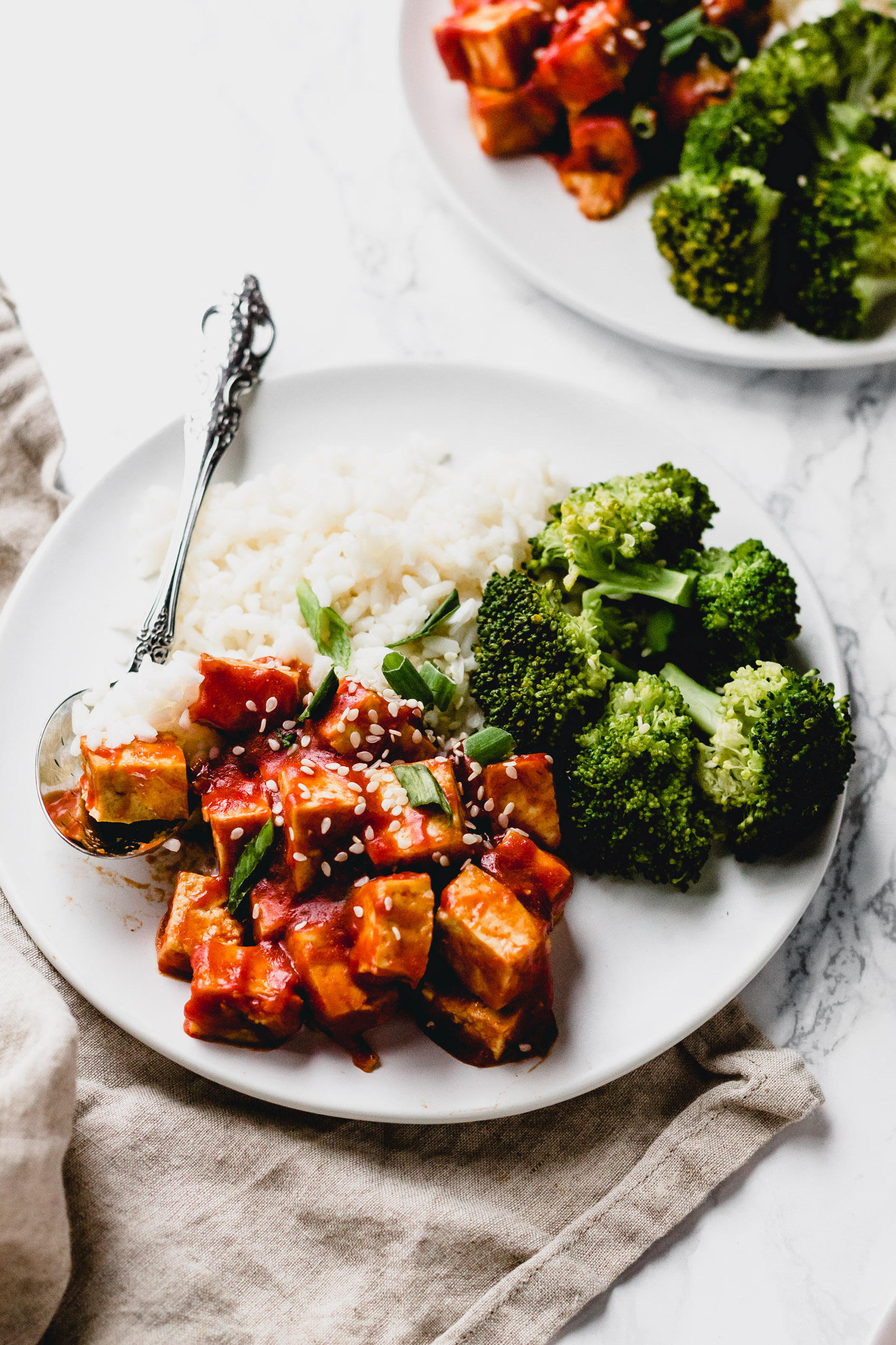 close-up side view of tofu in sweet and sour sauce with a spoon