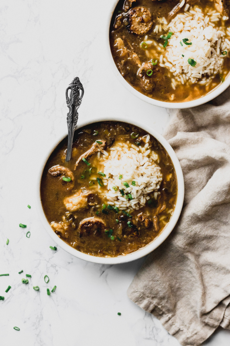 overhead shot of two bowls of thin brown soup with rice on top