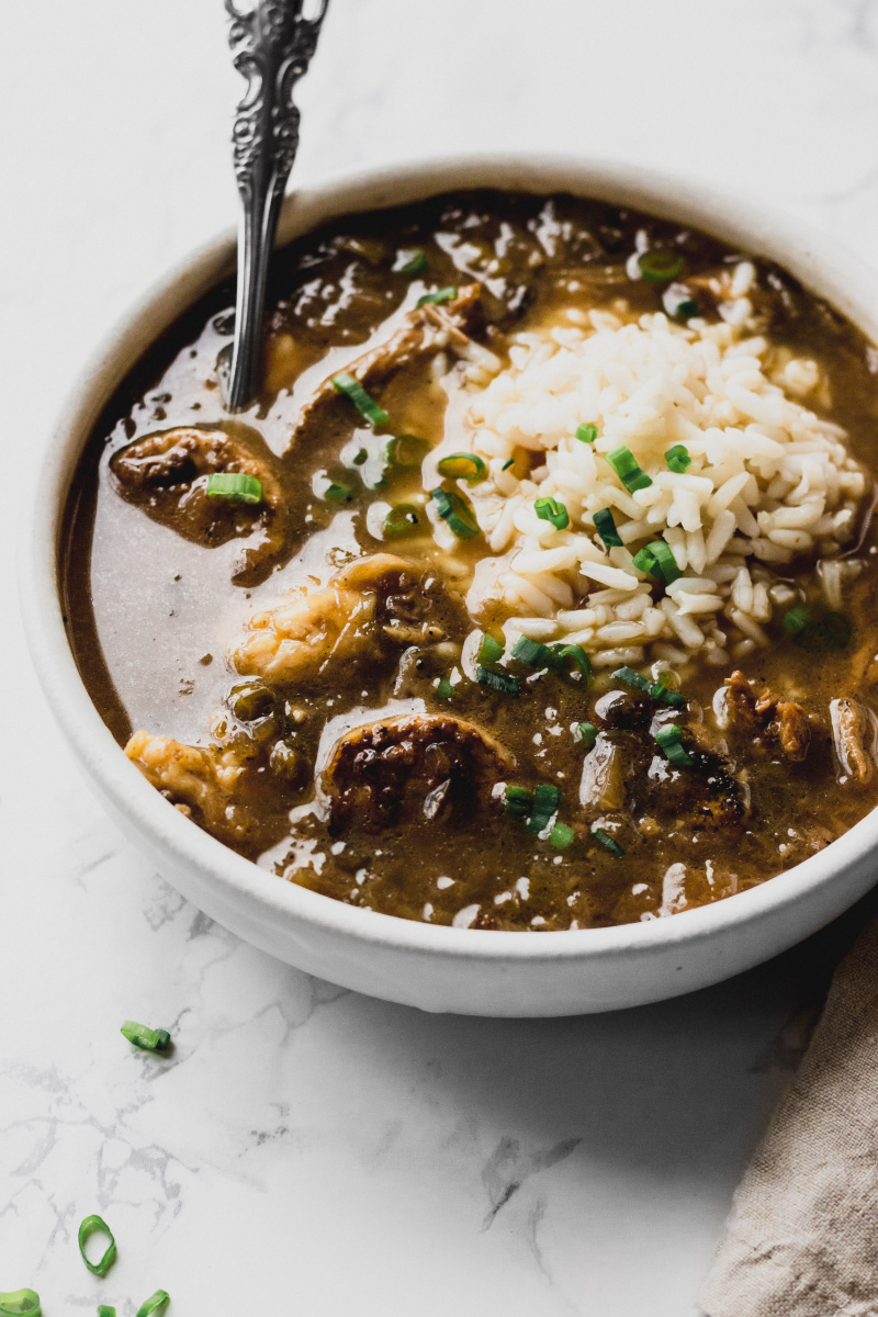 close-up of a bowl of brown broth with sausage, chicken, and rice