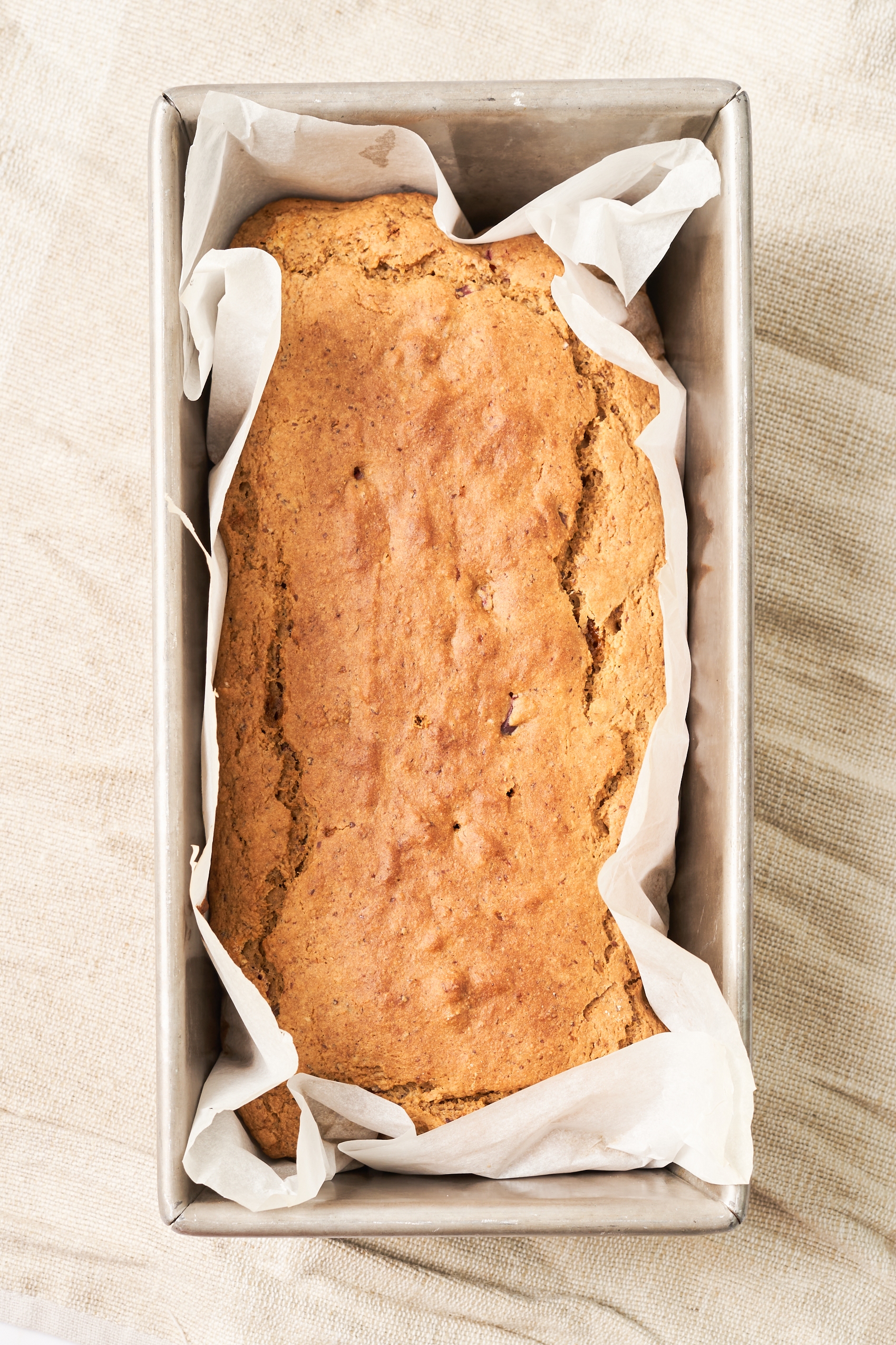 a loaf of cranberry orange bread in a pan lined with parchment