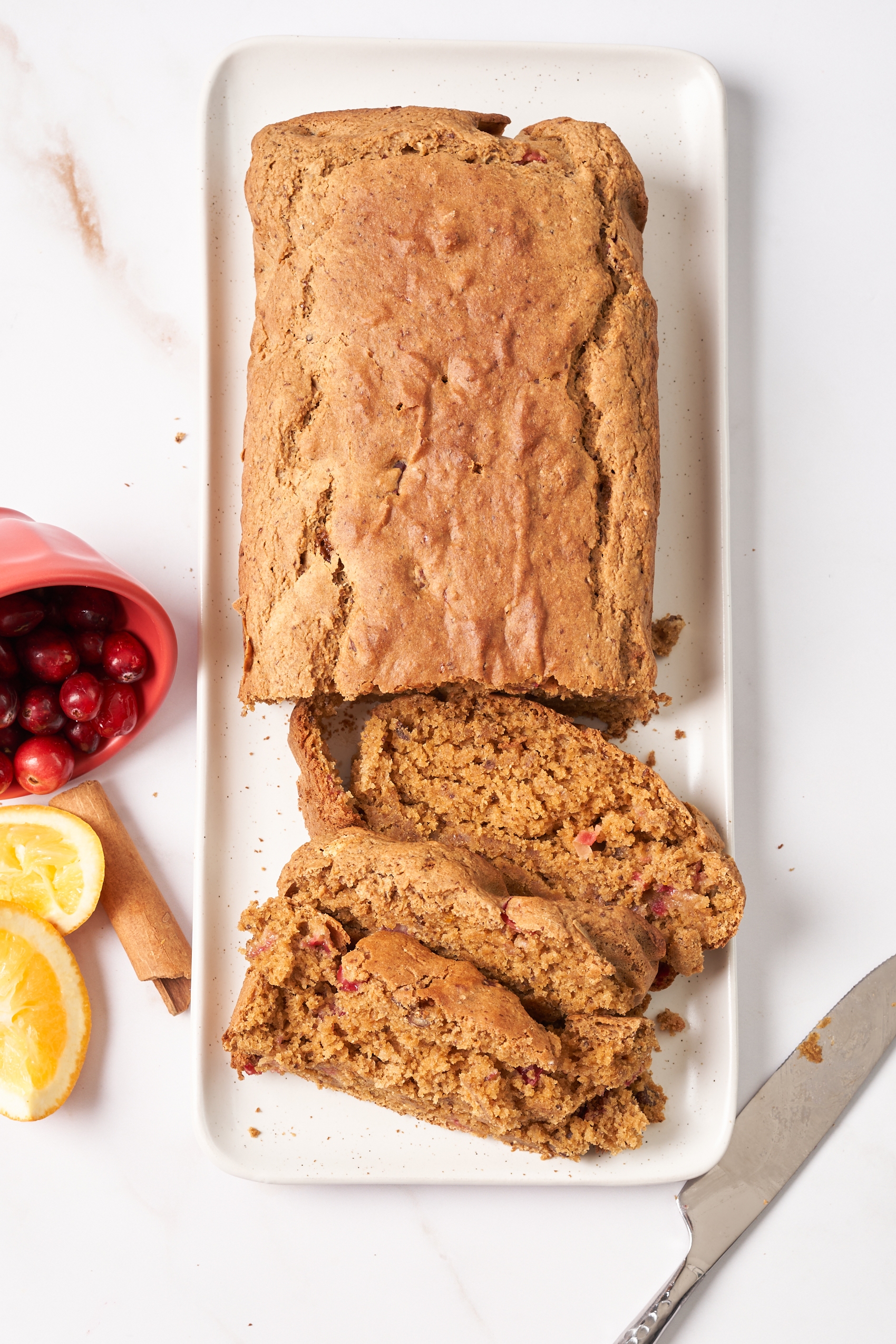 a loaf of vegan cranberry orange bread that has been cut into slices