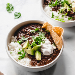 a bowl of black bean soup served with avocado and tortilla chips