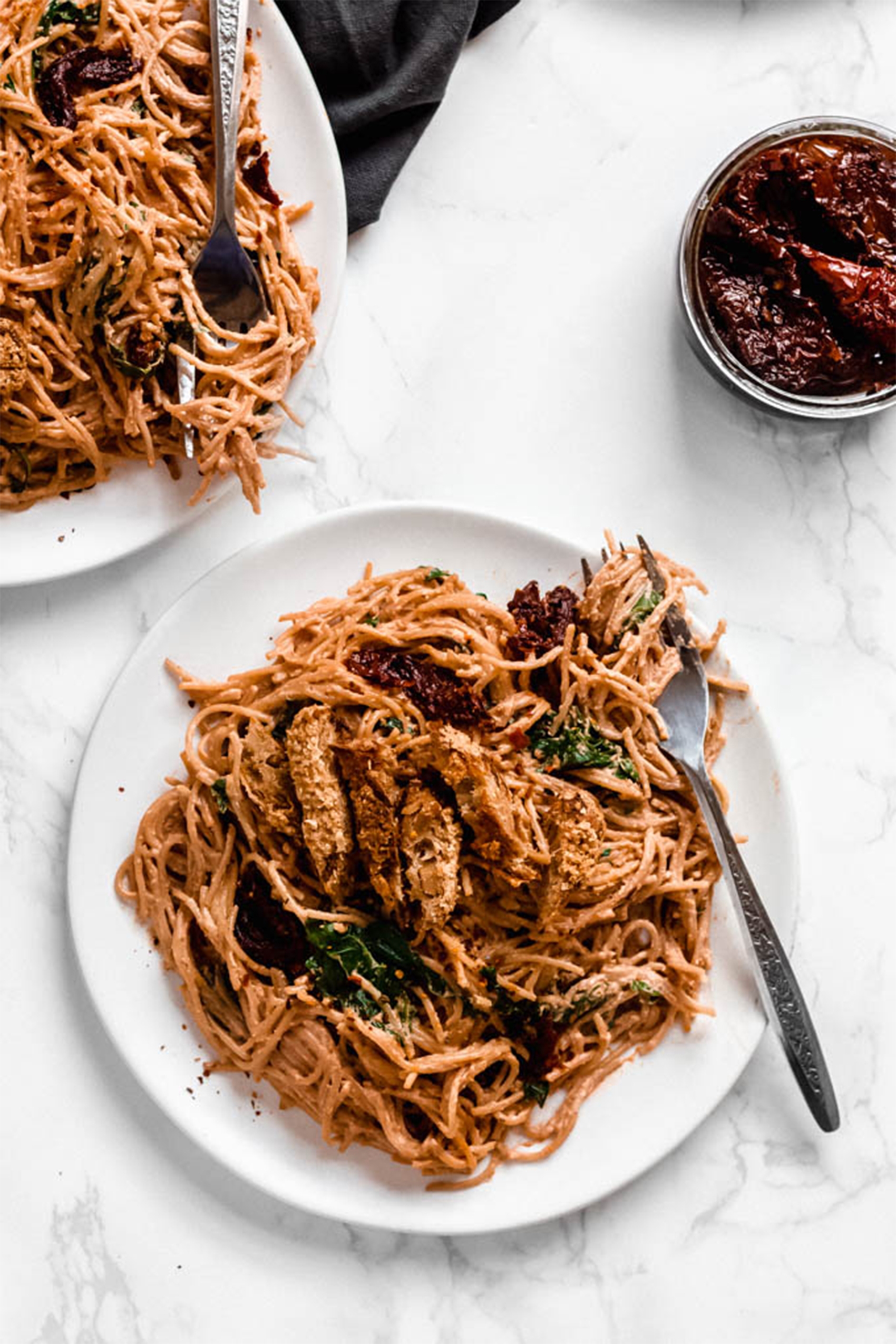 two plates of vegan sun dried tomato pasta