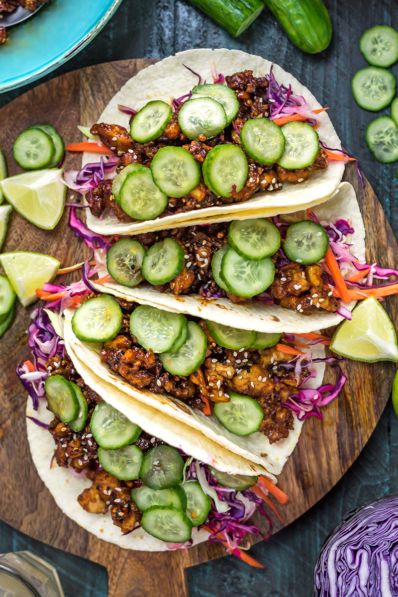 a platter of four korean inspired tacos topped with cucumber slices
