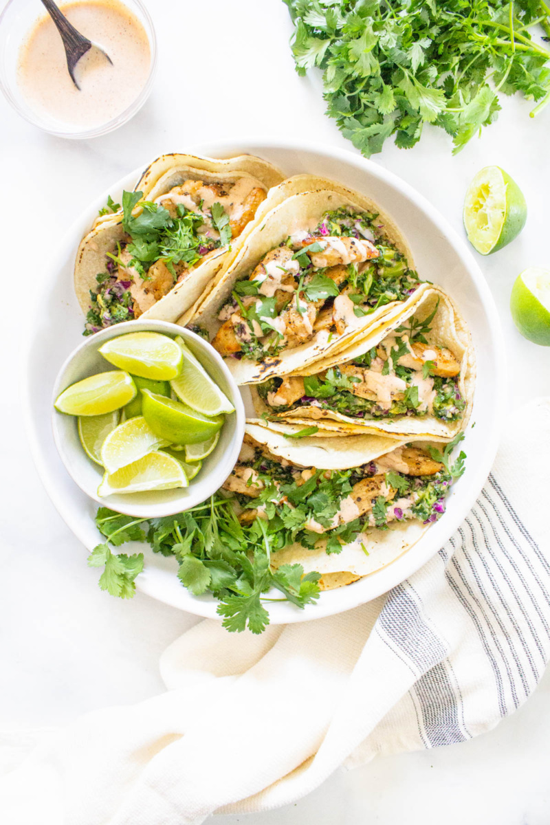 a plate of vegan chicken tacos served with limes