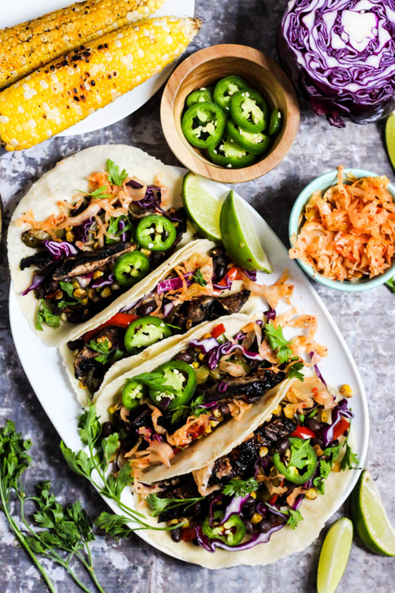 A platter of portobello mushroom tacos served with jalapenos, corn and kimchi