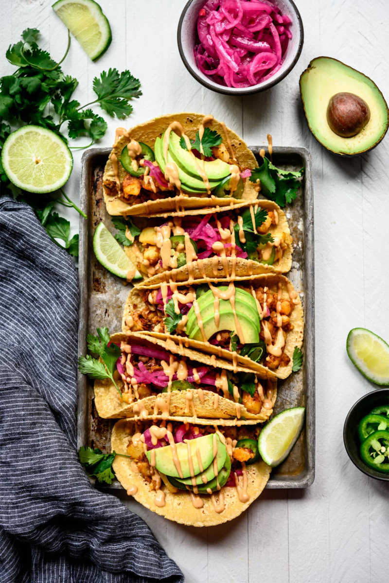 a tray of vegan tacos topped with avocado and cilantro