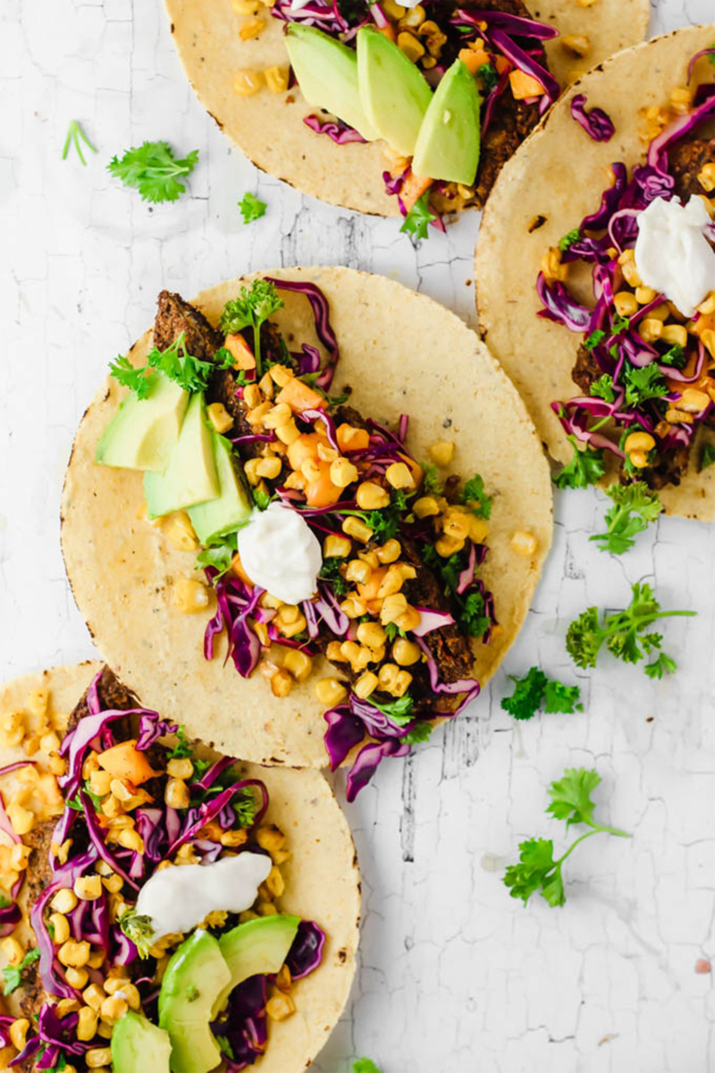 Roasted corn tacos topped with vegan sour cream and sliced avocado