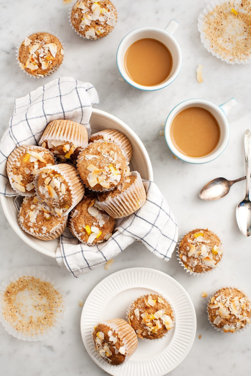 Mango coconut muffins served in a white bowl alongside two cups of coffee