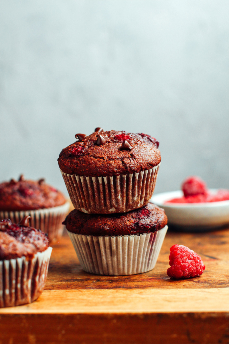 Two chocolate raspberry muffins are stacked on top of one another