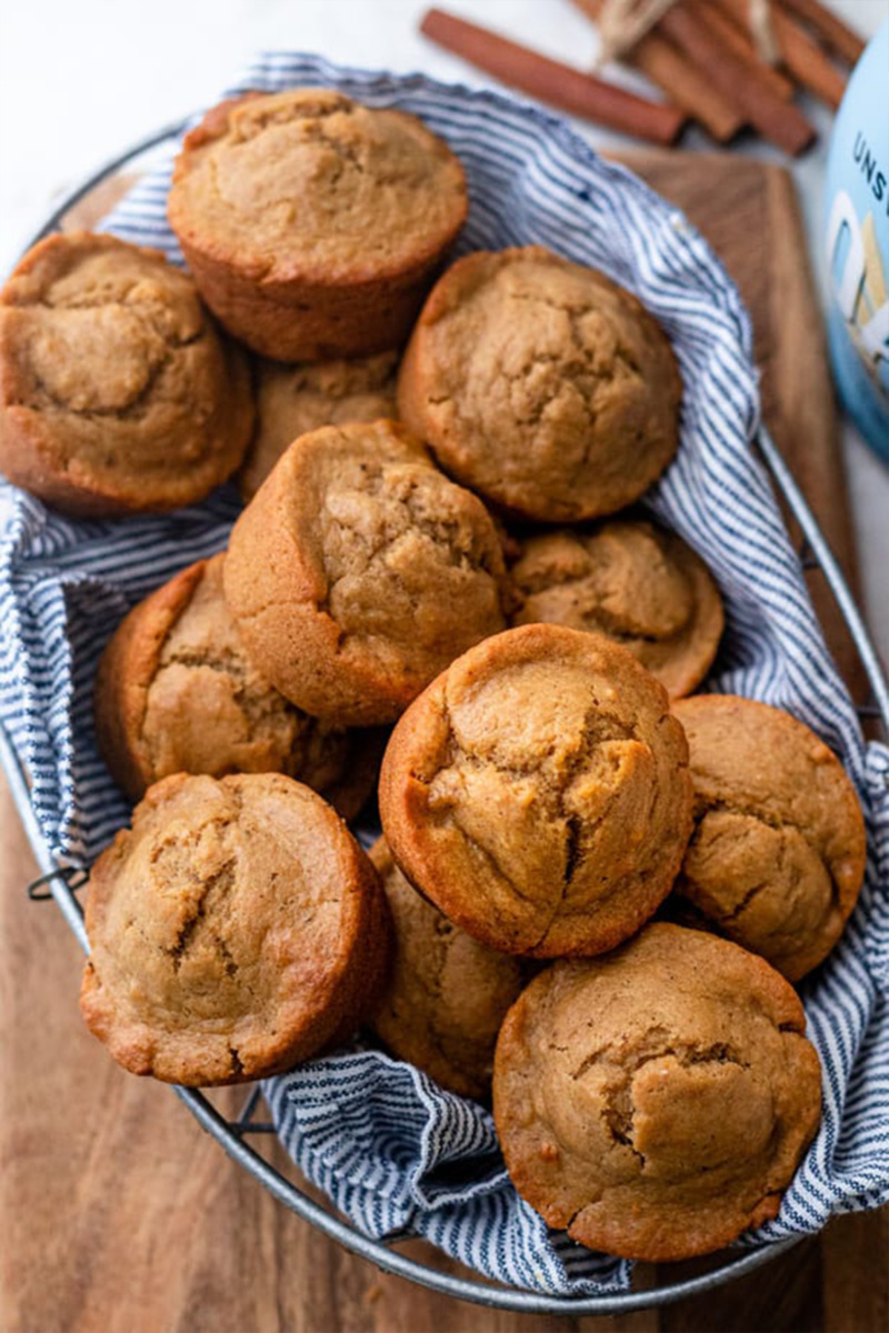 A basket lined with a blue and white striped towel is filled with chai spiced muffins