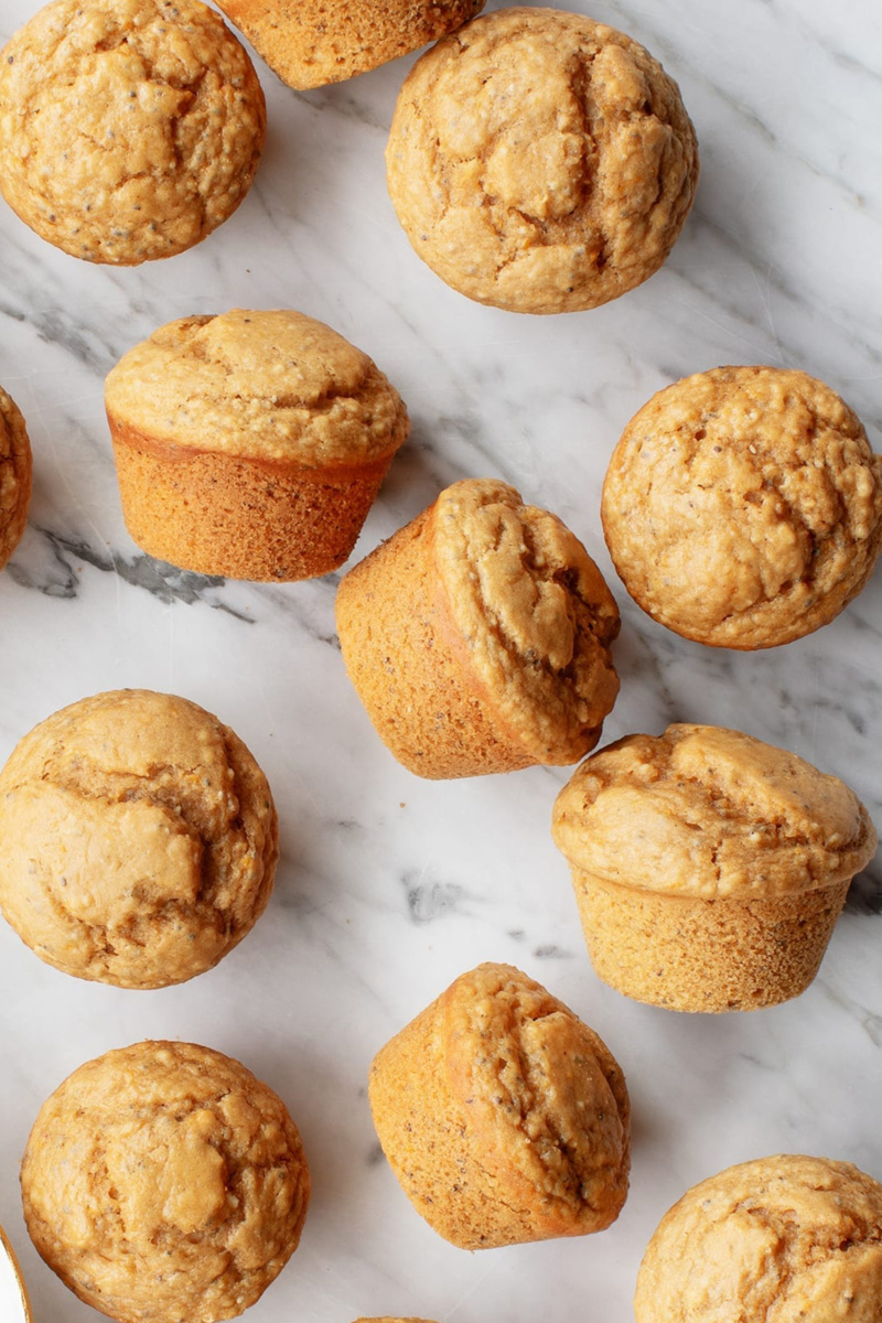 vegan lemon poppyseed muffins scattered across a marble countertop