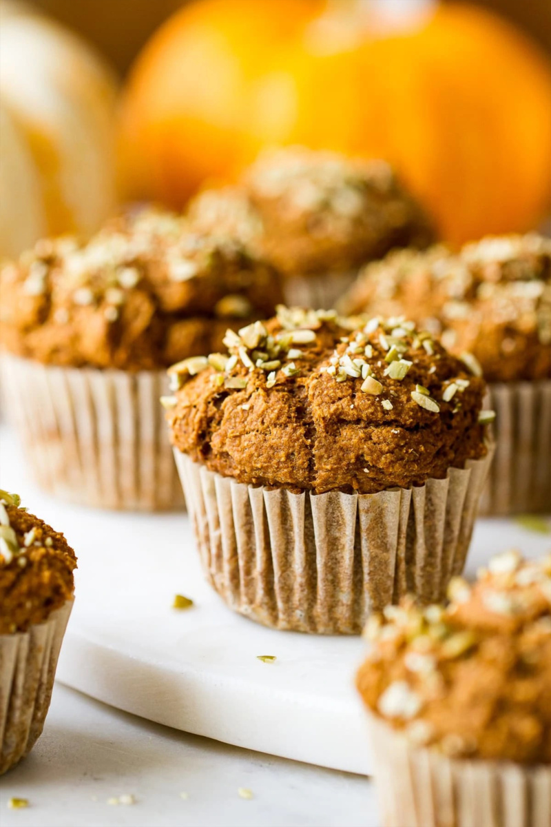 a plate of vegan pumpkin muffins served in front of a pumpkin